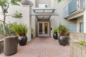 Enter a sleek, contemporary building with a covered walkway and lush greenery.