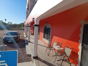 Ein Gebäude mit roter Fassade, weißen Säulen und einer kleinen Außenbereich-Sitzgelegenheit mit Stühlen und einem Tisch.