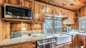 Una cocina con gabinetes de madera, electrodomésticos de acero inoxidable, encimeras de granito y lavavajillas.