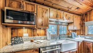 A kitchen with wooden cabinets, stainless steel appliances, granite countertops, and a dishwasher. - The Apple Tree | Tranquil Rio Ruidoso Cabin w/ Deck Views, River Sounds & Cozy Charm (Ruidoso)