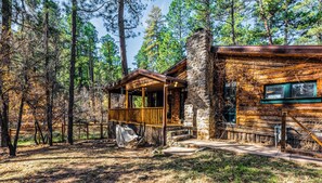 A rustic cabin with a wooden porch and stone walls, surrounded by a forest. - The Apple Tree | Tranquil Rio Ruidoso Cabin w/ Deck Views, River Sounds & Cozy Charm (Ruidoso)