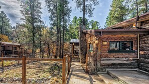 A rustic cabin with a stone chimney, wooden exterior, and a paved pathway leading to the entrance. - The Apple Tree | Tranquil Rio Ruidoso Cabin w/ Deck Views, River Sounds & Cozy Charm (Ruidoso)
