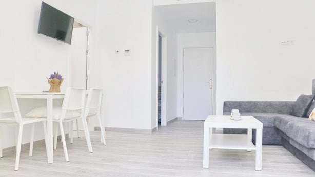 A modern living room with a grey sofa, a white coffee table, and a TV mounted on the wall. - Chalet del Sultan with pool and WiFI (Conil de la Frontera)