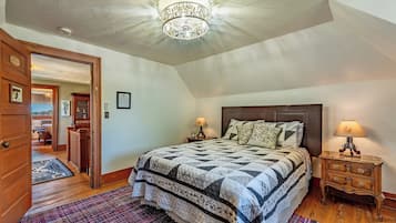 A bedroom with a large bed, two bedside tables with lamps, a wooden door, and a patterned rug.