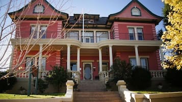 Stately two-story building with a central entrance and symmetrical facade, featuring a prominent gabled roof and decorative trim.