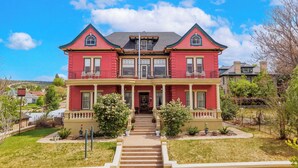 A two-story red house with a front porch and a staircase leading to the entrance.