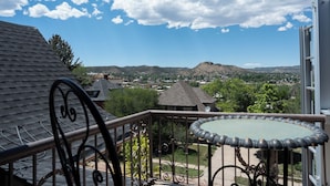 A balcony with a view of a town, a table, and a railing.