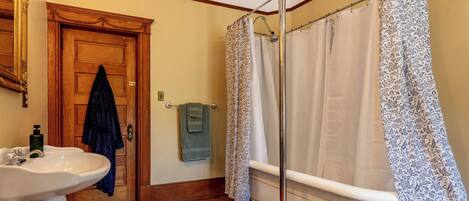 Un baño con dos lavamanos, una bañera, un cortinón de ducha y una puerta de madera.