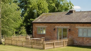 A brick house with a fenced patio, a chimney, and a large window. - Paddock Cottage - sleeps 2 guests  in 1 bedroom (Winchcombe)