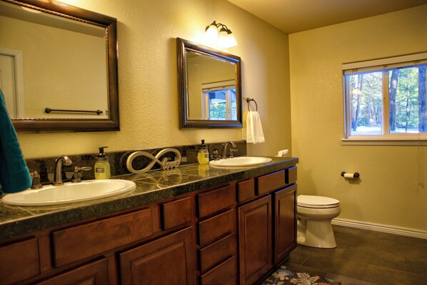 A bathroom with two sinks, a toilet, and a window.