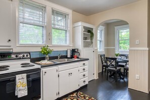 A kitchen with white cabinets, a stove, and a dining area with a table and chairs.