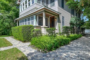 A two-story house with a front porch, a stone column, and a well-maintained garden.