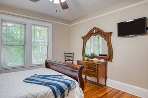 A bedroom with a bed, dresser, mirror, and television.