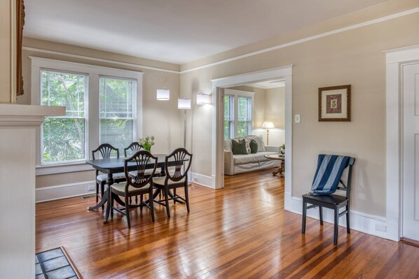 A dining area with a wooden table and chairs, a sofa, and a chair with a striped cushion.