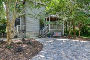 A two-story house with a covered porch, a staircase, and a patio area.