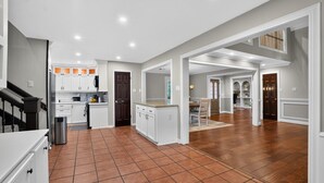 A spacious kitchen with white cabinets, a dining area with a table and chairs, and a staircase leading to an upper level. - Four bedroom  in United States of America, Tomball (Tomball)