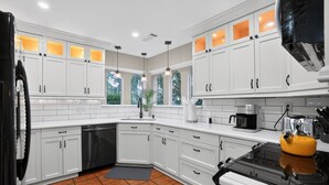 A modern kitchen with white cabinets, a black refrigerator, a yellow kettle, and a coffee maker. - Four bedroom  in United States of America, Tomball (Tomball)