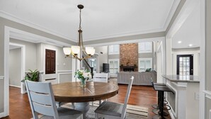 A dining area with a round wooden table, four chairs, a chandelier, and a brick fireplace. - Four bedroom  in United States of America, Tomball (Tomball)