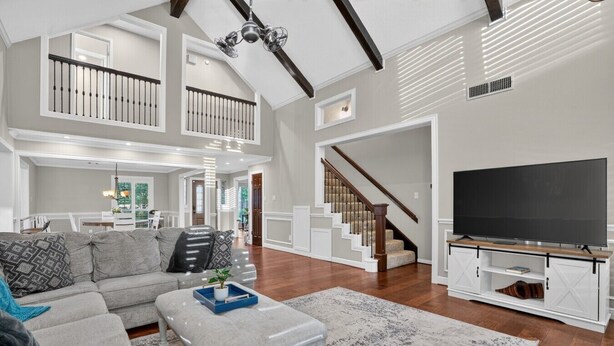 A spacious living room with a large sectional sofa, a coffee table, a flat-screen TV on a stand, a staircase, and a view of the dining area. - Four bedroom  in United States of America, Tomball (Tomball)