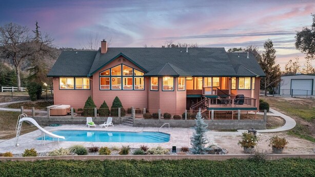 A two-story house with a swimming pool, a covered deck, and a fenced yard.
