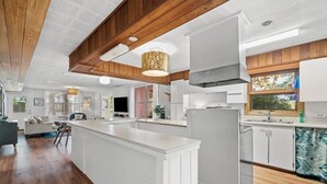 Una cocina moderna con armarios blancos, una isla central y un refrigerador grande.