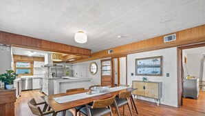 Una cocina moderna con armarios de madera, una isla central y un área de comedor con mesa y sillas de madera.