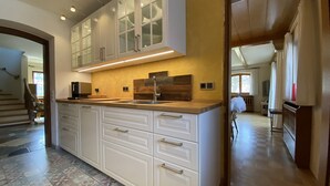 A spacious kitchen with white cabinetry, a large island, and a modern backsplash. - Vacation home Blindauer Eck 160 sqm with mountain view (Reit im Winkl)