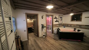 A room with wooden flooring, a large bed, a bedside table, a wall-mounted TV, and a ceiling light. - Vacation home Blindauer Eck 160 sqm with mountain view (Reit im Winkl)