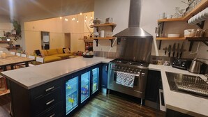 Une cuisine moderne dotée d’un îlot central, d’appareils électroménagers intégrés et d’un coin repas avec un canapé jaune.