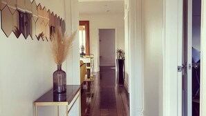 Un couloir doté d’un parquet en bois foncé, d’une console sur laquelle sont posés un vase et des plumes d’herbe des pampas, et d’un mur entièrement recouvert de miroirs.
