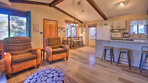 A spacious living room with a high ceiling and exposed beams, a kitchen with modern appliances, and a cozy seating area with patterned chairs. - Patio, Grill + Mogollon Rim Views: Payson Cabin (Payson)