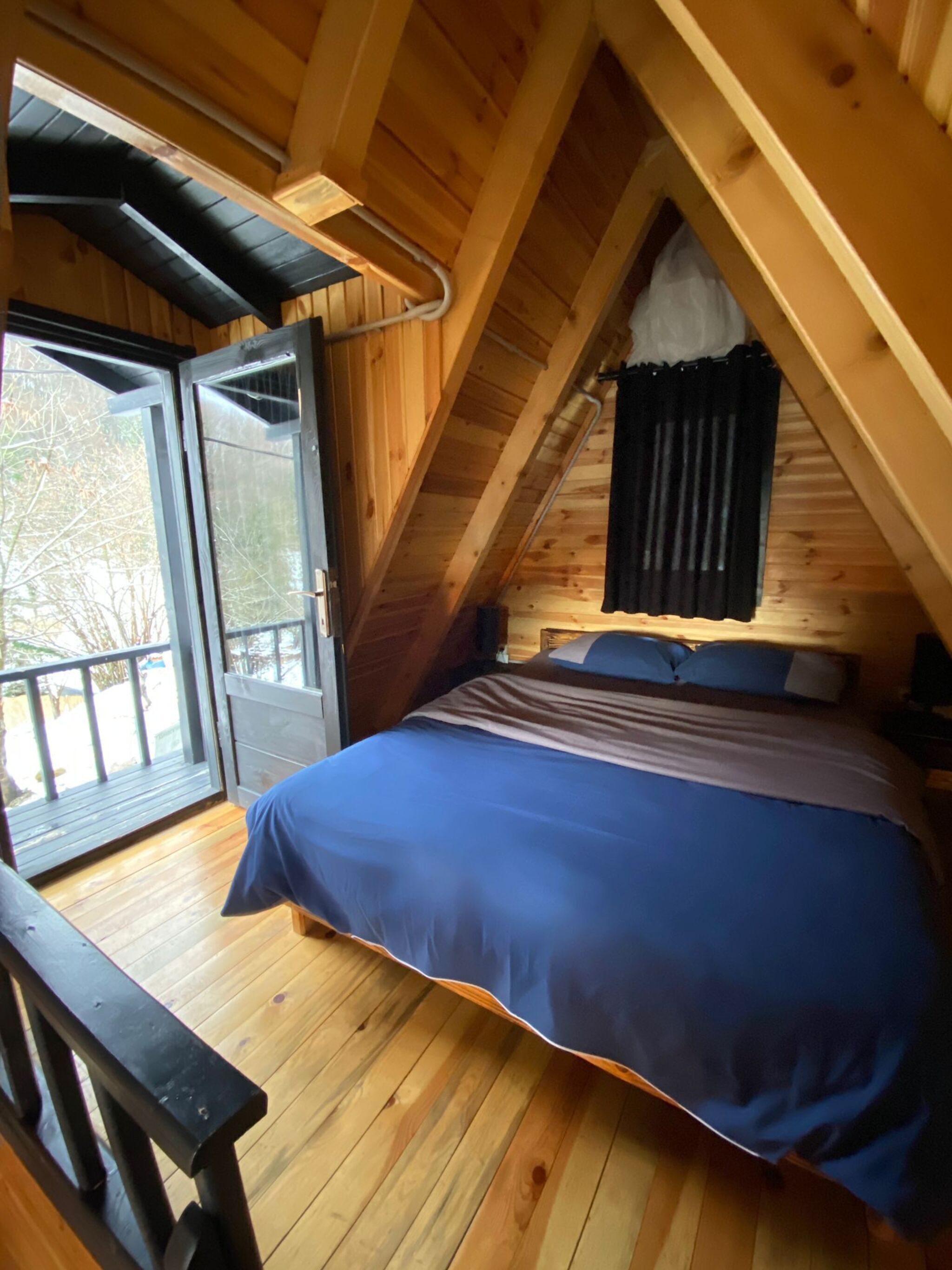 A bedroom with a bed, a window, and a door leading to an outdoor area.