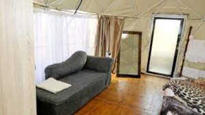 Una habitación con tienda, un sofá, una cama con estampado de leopardo y una puerta corrediza de vidrio.