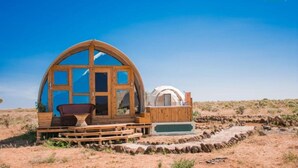 Una estructura de madera con un gran ventanal arqueado y una tienda en forma de cúpula más pequeña.