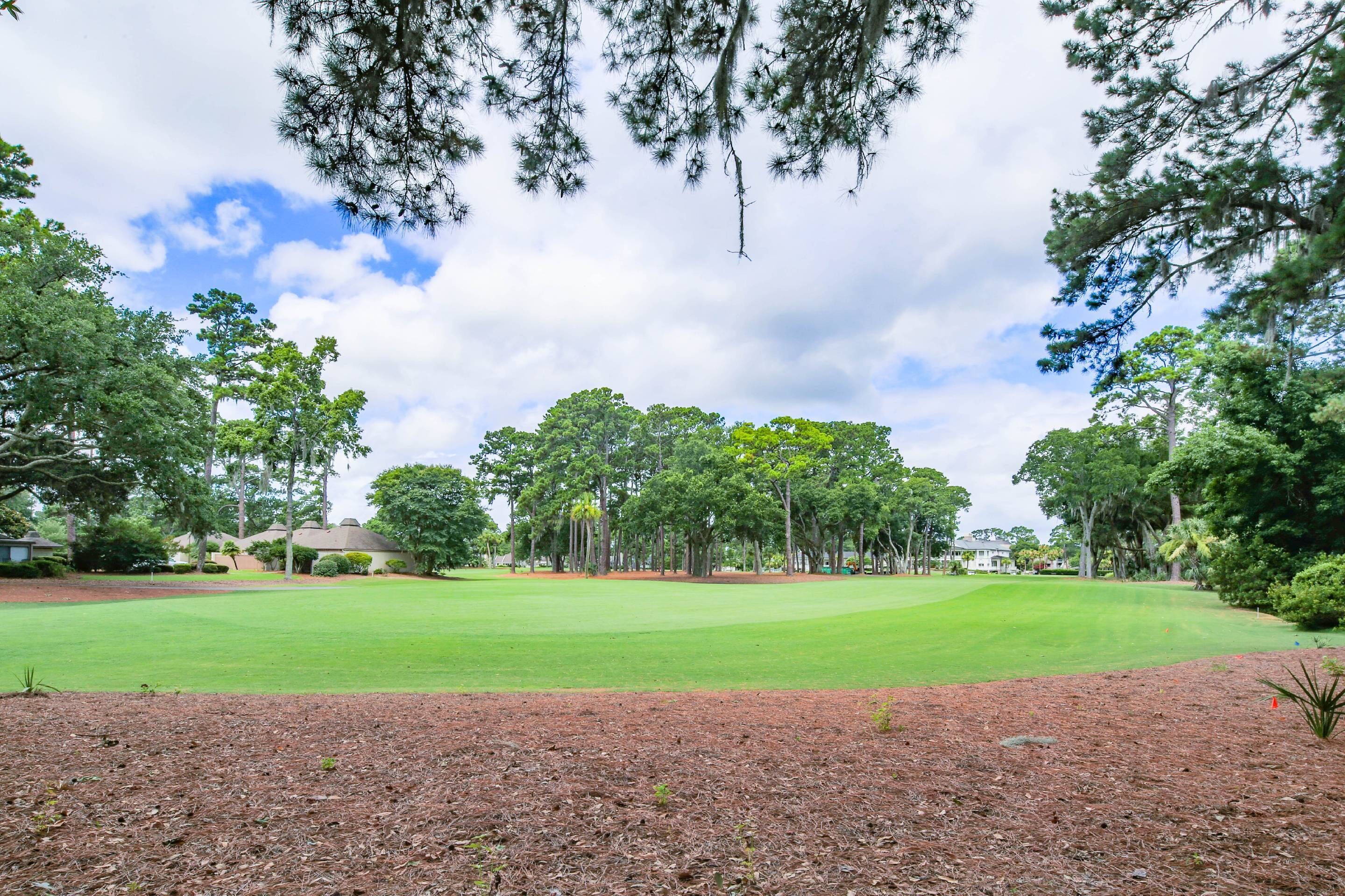 Un parcours de golf avec un terrain verdoyant bien entretenu, entouré d’arbres et sous un ciel dégagé.
