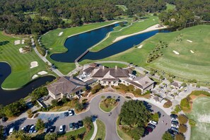 Luftaufnahme eines Golfplatzes mit Clubhaus, mehreren Teichen und Parkplätzen.