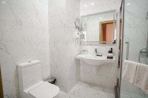 Un baño moderno con inodoro, lavabo y cabina de ducha de vidrio.
