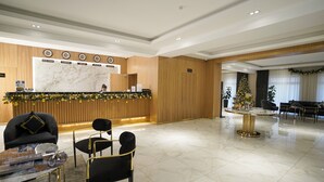 A hotel lobby with a reception desk, seating area, and a Christmas tree. - Milan Hotel (Tashkent)