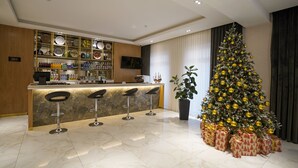 A modern kitchen with a bar area, a large Christmas tree, and neatly wrapped presents. - Milan Hotel (Tashkent)