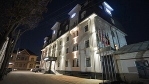 A multi-story hotel with a classic architectural design, featuring a prominent entrance and multiple flags displayed outside. - Milan Hotel (Tashkent)