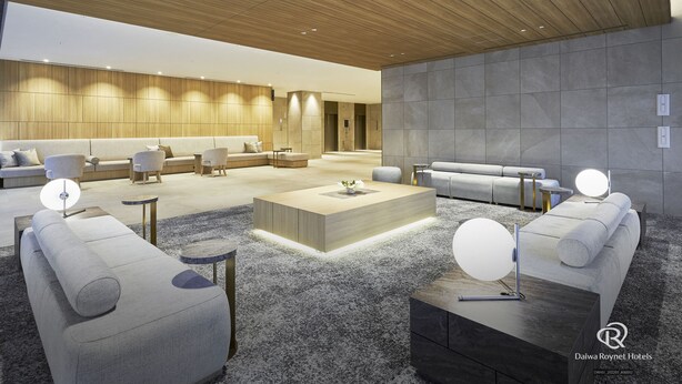 A spacious hotel lobby with a modern design, featuring a wooden ceiling, grey sofas, and a central coffee table. - Daiwa Roynet Hotel Sendai-nishiguchi PREMIER (Sendai)