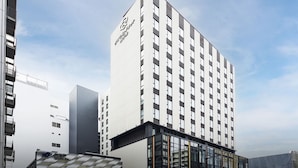 Un hôtel Daiwa Roynet au design moderne, caractérisé par un logo bien visible sur la façade, de grandes fenêtres et un espace d’entrée abrité.