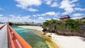 A coastal view with a bridge, beach, and traditional building. - APA Hotel Naha Airport Wakasa (Naha)