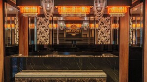 A lobby with a marble reception desk, chandeliers, and patterned wallpaper. - APA Hotel Naha Airport Wakasa (Naha)