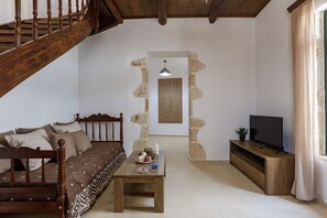 A cozy living room with a wooden staircase, a sofa, a coffee table, and a television.