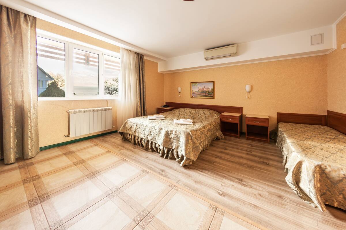 Cozy retreat with a large bed, bedside tables, and a nightstand, plus a window with curtains and a radiator.