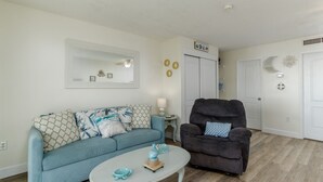 Un salon avec un canapé bleu clair, un fauteuil foncé et une table basse blanche.