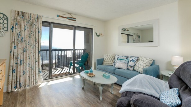 Un salon avec un canapé, une table basse et un balcon offrant une vue agréable.