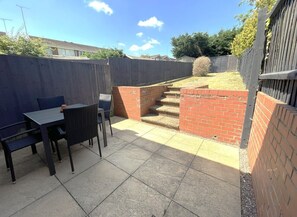 A patio area with a table and chairs, a brick wall, and a wooden fence.