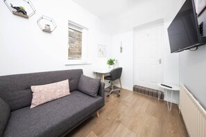Relax in this stylish room with a sofa, desk, and TV.